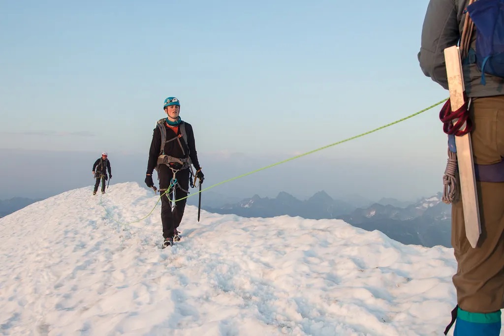 کوهنوردانی که با طناب به یکدیگر وصل شده اند در حال کوهنوردی در یک منطقه برفی